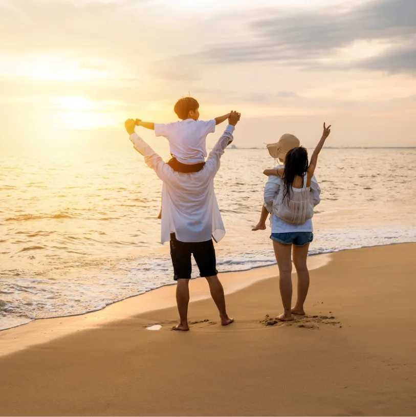 Famille sur la plage devant un coucher de soleil